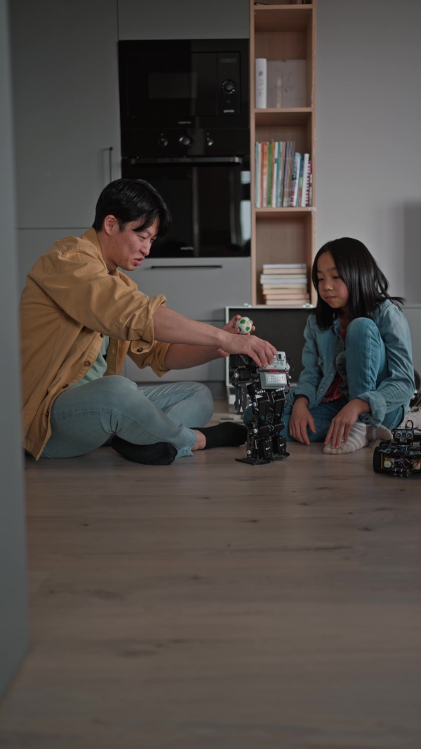 Father teaching his curious daughter about STEM, robotics, and discussing technology while playing with the robot.
