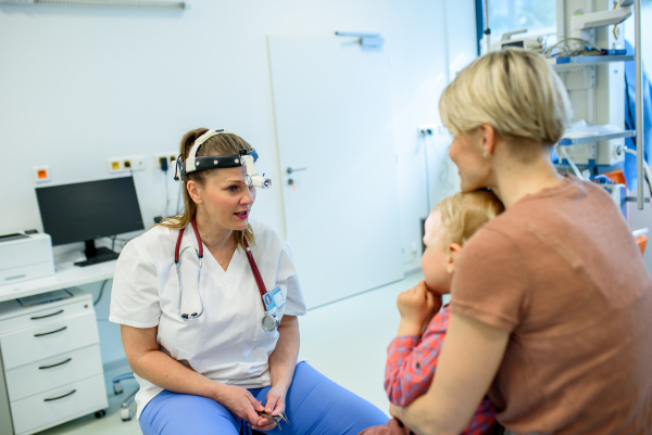 Otolaryngologist examining toddler in pediatric clinic, ENT exam.