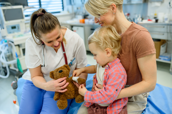 Doctor and young toddler patient treat a teddy bear during medical check up.