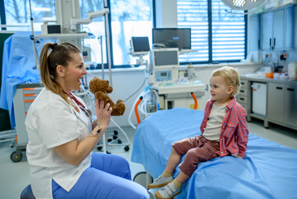 Female pediatrician comforting little boy with teddy bear during checkup