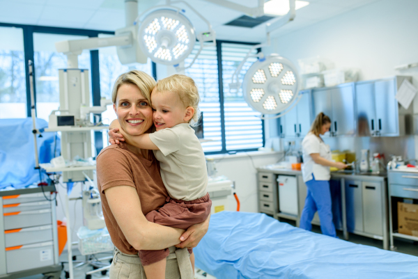 Portrait of beautiful mother with little toddler son during examination in medical clinic. Preventive care.