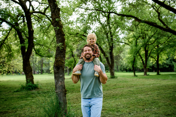 Dad carrying his smiling son on shoulders during walk in park