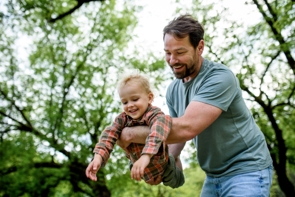 Father playing with toddler son outdoors in city park