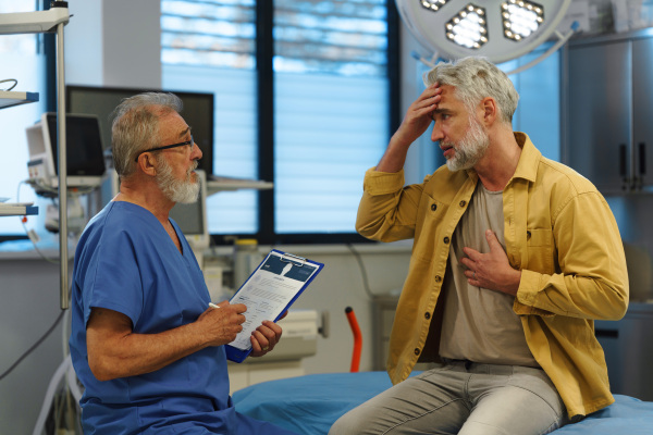 Patient sitting on examination table, describing health problems and symptoms to doctor.