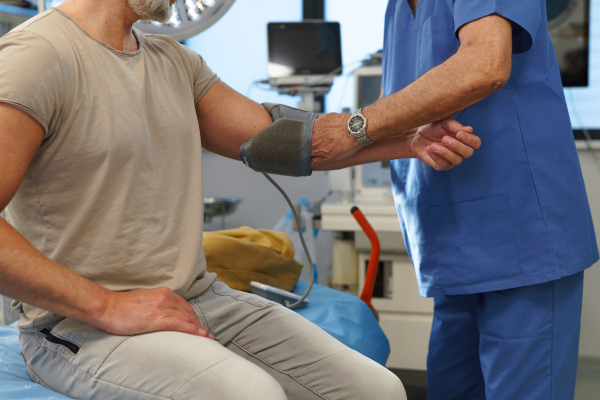 Doctor taking patient's blood pressure using a digital blood pressure monitor.
