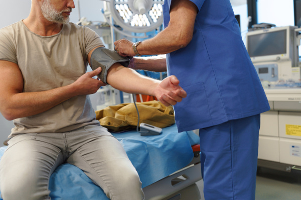 Doctor taking patient's blood pressure using a digital blood pressure monitor.