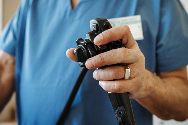 Close-up of doctor holding endoscope control in gastroenterology unit.