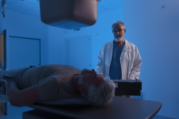 Male patient undergoing X-ray examination using a tilting radiographic wall stand.
