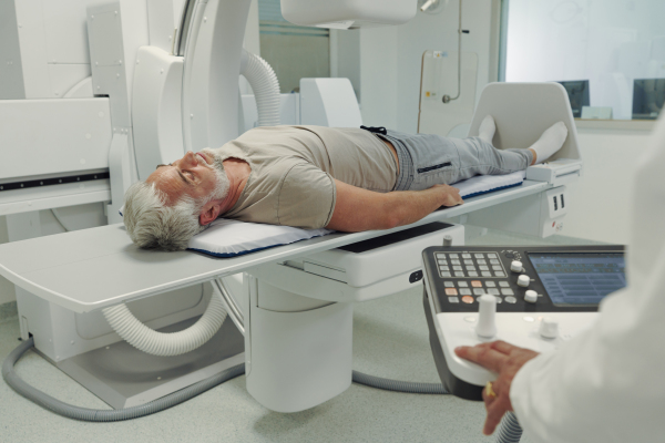 Doctor operationg CT machine in hospital. Male patient undergoing CT scan.
