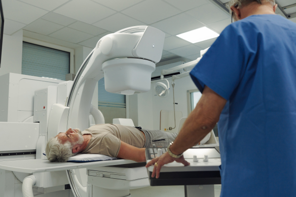 Doctor operationg CT machine in hospital. Male patient undergoing CT scan.