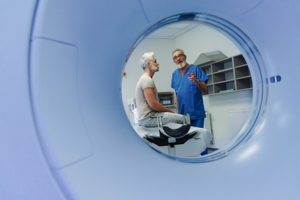Doctor explaining CT scan results to male patient in hospital setting