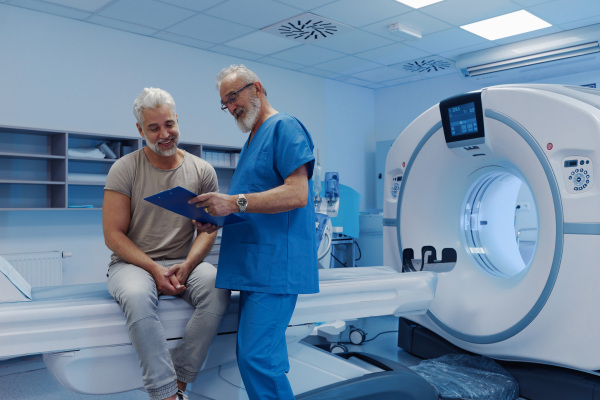 Doctor explaining CT scan results to male patient in hospital setting