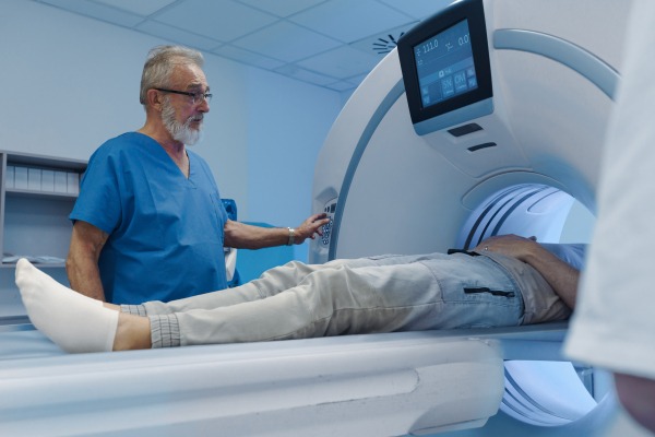 Doctor operationg CT machine in hospital. Male patient undergoing CT scan.