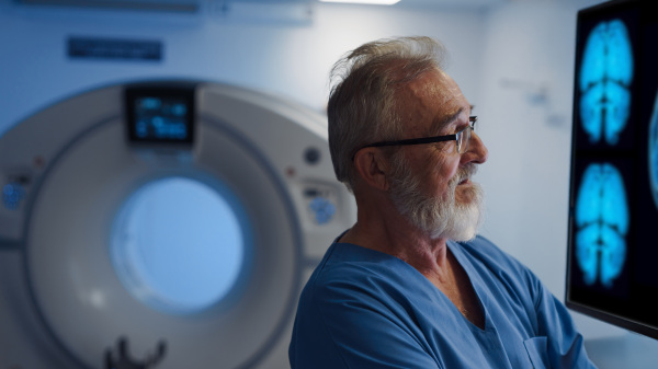 Portrait of doctor looking at CT scans of brain. Hospital setting.