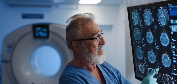 Portrait of doctor looking at CT scans of brain. Hospital setting. Banner with copy space.