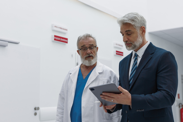 Doctor talking with hospital manager, showing him document.