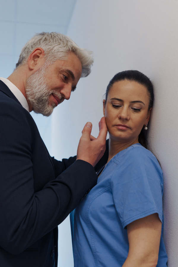 Pharmaceutical representative or hospital manager harassing attractive nurse in healthcare setting.