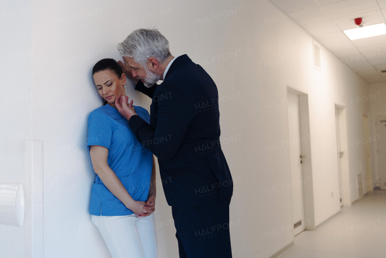 Pharmaceutical representative or hospital manager harassing attractive nurse in healthcare setting.