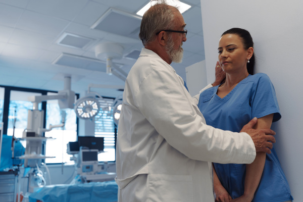 Inappropriate behavior between senior doctor and female nurse in hospital hallway. Workplace harassment.