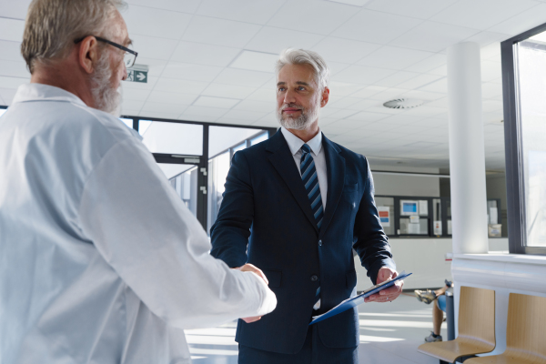 Portrait of manager shaking hand with doctor. Hospital director, hospital setting.