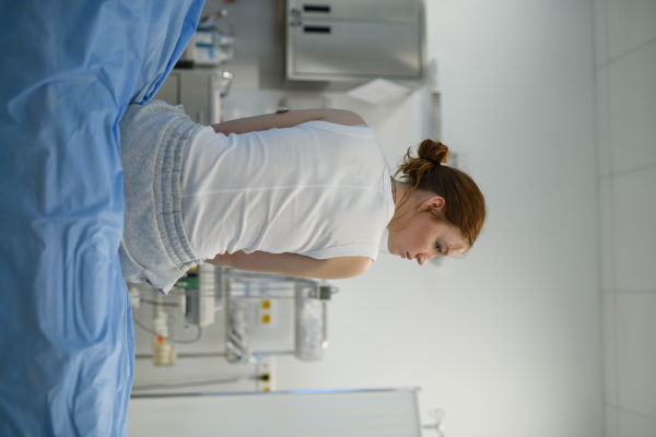 Rear view of teenage girl waiting for medical examination in hospital. Portrait of adolescent patient.