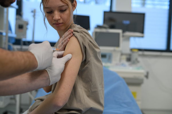 Teenage girl receiving vaccination during routine health checkup at hospital.
