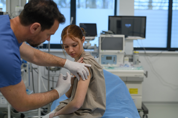 Teenage girl receiving vaccination during routine health checkup at hospital.