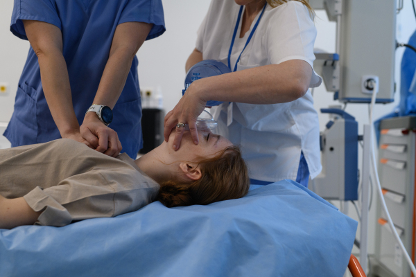 Doctors performing CPR on teenage patient in critical condition, emergency resuscitation.