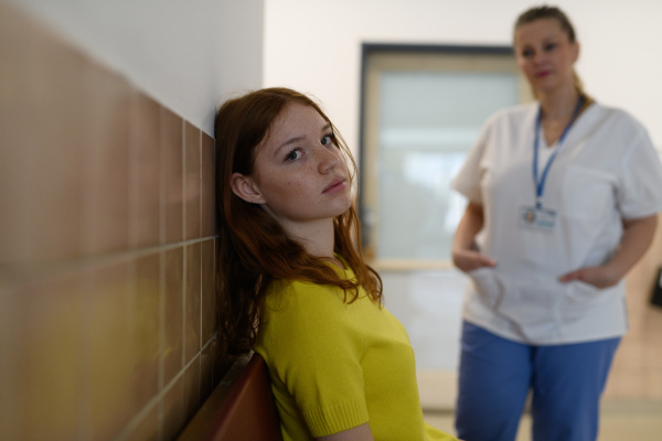 Teenage girl waiting alone in hospital waiting area before preventive medical checkup.