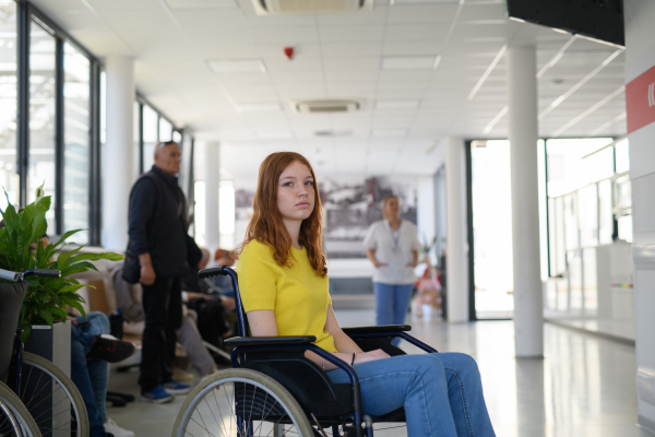 Young female patient in wheelchair at hospital, modern clinic.