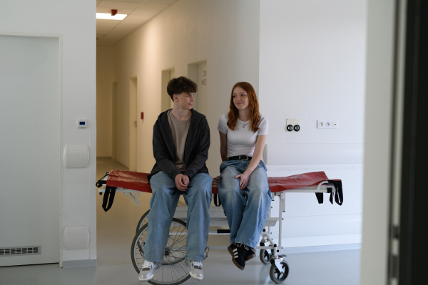 Boy and girl waiting in hospital waiting room for medical examination, looking at each other.