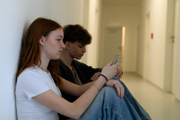 Boy and girl waiting in hospital waiting room for medical examination, side view.