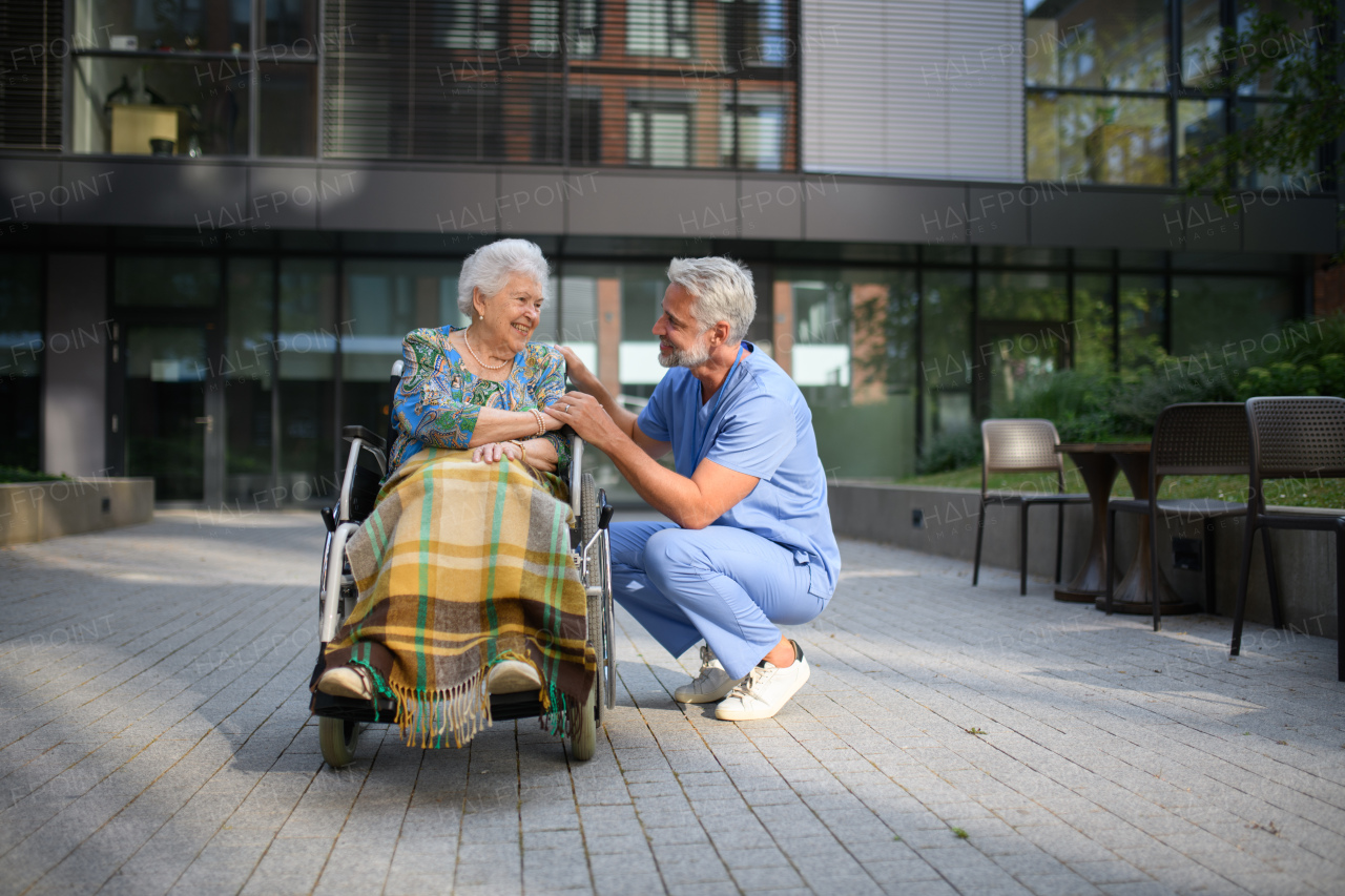 Male caregiver talking with senior woman in a wheelchair.