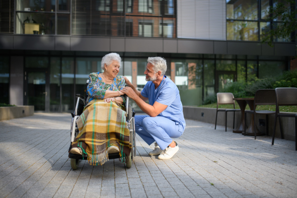 Male caregiver talking with senior woman in a wheelchair.