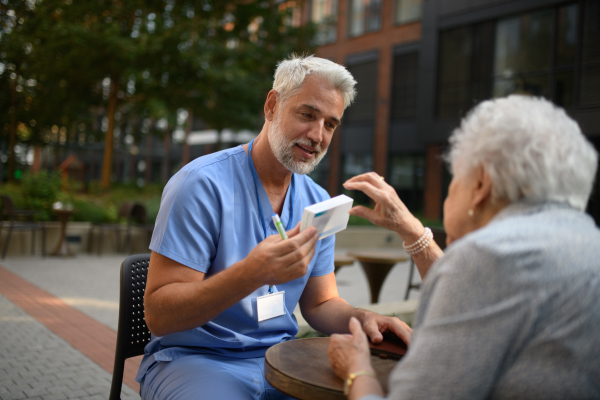 Doctor explaining medication to senior patient and answering her questions about diagnosis.