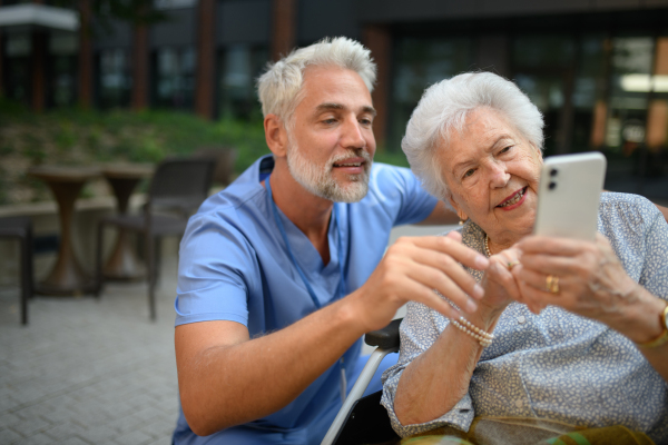 Male caregiver looking at photos with senior woman in a wheelchair.