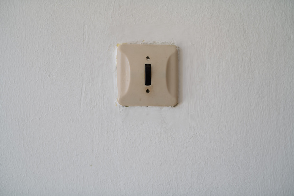 Old light switch on white wall in outdated building