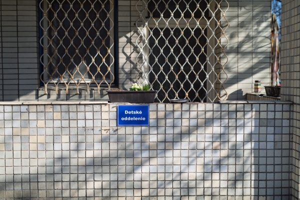 Sign for children's hospital department with barred windows and worn facade