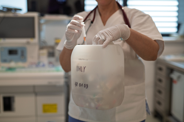 Nurse disposing of used syringe into needle waste container
