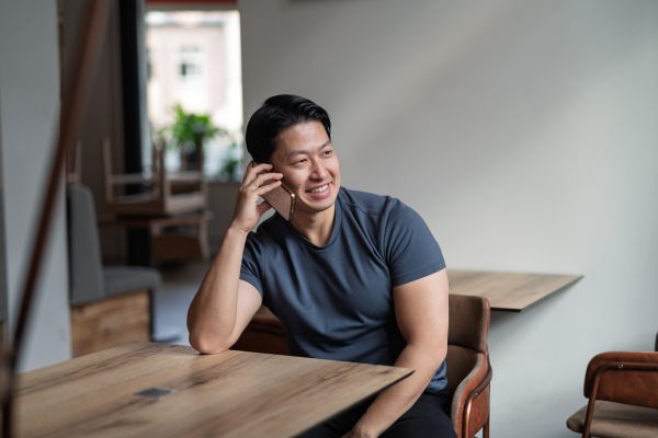Confident young man having phone call at cafe table.