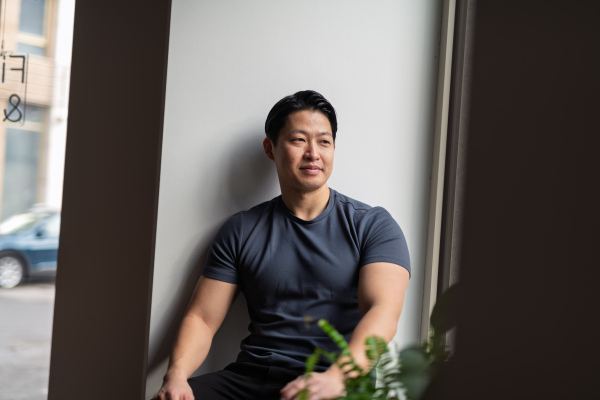 Confident young man sitting by the window in natural light, resting.