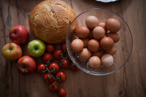 Fresh ingredients for homemade breakfast. Eggs, bread and fruit on rustic wooden table.