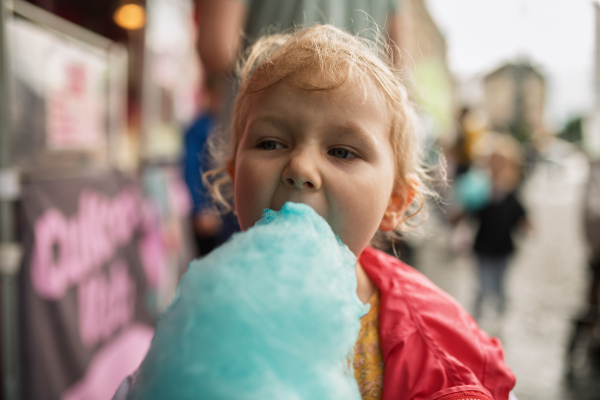Cute kid eating blue cotton candy outdoors