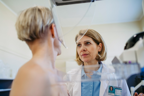 Healthcare professional adjusts the patient for accurate breast imaging. Preventive breast cancer screening.