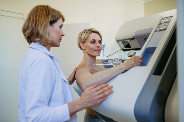 Medical worker positioning patient for precise breast scan, mammogram. Preventive breast cancer screening.