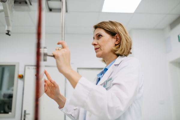 Female doctor operating dynamic X-ray scan using tilting fluoroscopy unit