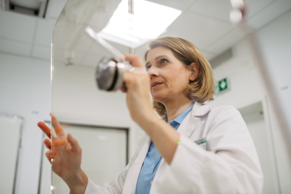 Female doctor operating dynamic X-ray scan using tilting fluoroscopy unit