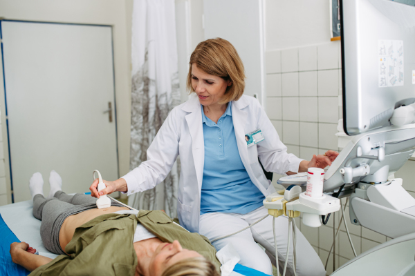Doctor performing diagnostic ultrasound during preventive care. Abdominal sonography.