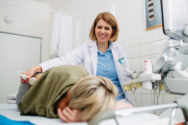 Medical examination with ultrasound probe on lower back. Kidney or pelvic ultrasound