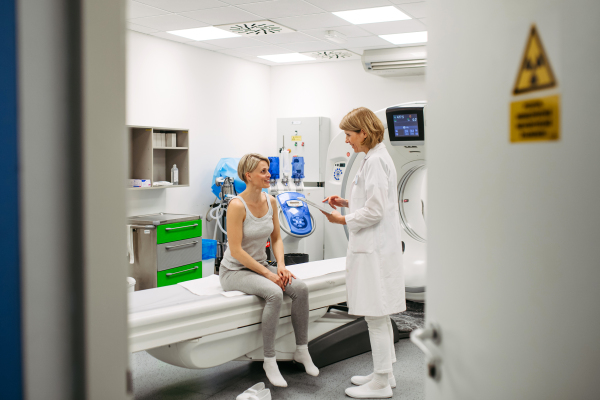 Doctor sharing positive CT scan results with smiling patient in imaging room, medical setting.